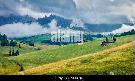 Dramatische Morgenszene des Dorfes Compacio mit Langkofel im Nebel, Lage auf der Seiser Alm oder der Seiser Alm, Provinz Bozen, Italien, Europ Stockfoto