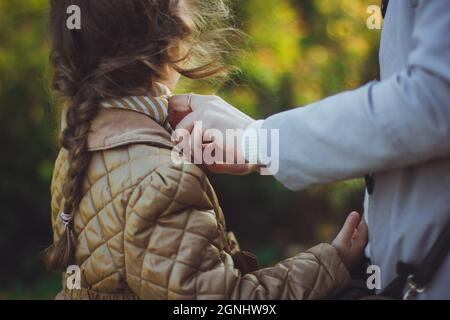 Mama fastet Jacke an ihre Tochter Stockfoto