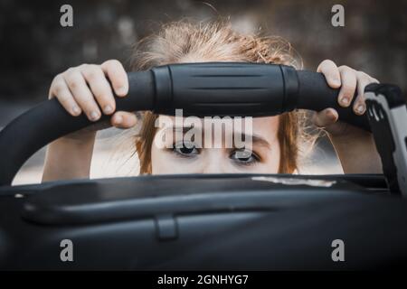 Eine seichte Aufnahme eines niedlichen kleinen Mädchens aus Kroatien mit einem Kinderwagen-Geländer Stockfoto