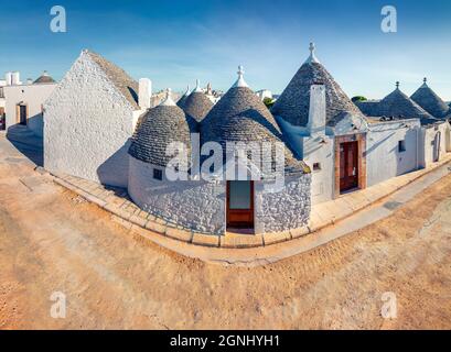 Unglaublicher Blick auf die Straße mit Trullo (Trulli) - traditionelle apulische Trockensteinhütte mit einem kegelförmigen Dach. Sonniges Stadtbild von Alberobello im Frühling Stockfoto