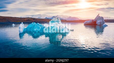 Blick von der fliegenden Drohne auf das Schweben von blauen Eisbergen in der Jokulsarlon Glacier Lagoon. Beeindruckender Sonnenuntergang im Vatnajokull Nationalpark. Atemberaubender Abend Stockfoto