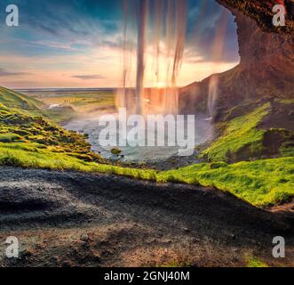Populaк Touristenziel - Seljalandsfoss Wasserfall, wo Touristen hinter dem fallenden Wasser spazieren können. Spektakuläre Sommerszene von Island, Europa Stockfoto