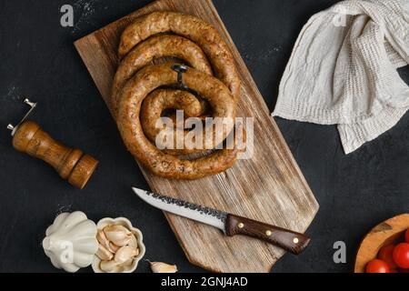 Pferdefleischwurst mit Knoblauch auf Holzschneidebrett gerollt Stockfoto