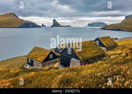 Düstere Herbstszene von Bour Village mit typischen Turf-Top-Häusern und Tindholmur Klippen im Hintergrund. Attraktive Morgenansicht der Insel Vagar, Färöer, Stockfoto