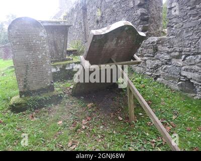 Rettung eines Grabsteines vor dem Sturz auf dem Gelände der Monigaff (Minnigaff) Kirche oder Kirk , in der Nähe von Newton Stewart, Dumfries und Galloway. Die "neue" Kirche ist eine Kirche unter dem B-Denkmalschutz, die 1836 nach einem neugotischen Entwurf von William Burn erbaut wurde. Innerhalb des gleichen Geländes befinden sich die Ruinen der alten Kirche mit dazugehörigen Begräbnissen, die mit alten Grabsteinen markiert sind. Es wurde an der Stelle eines älteren motte- und bailey-Schlosses errichtet Stockfoto