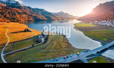 Blick von der fliegenden Drohne. Spannende Herbstszene des Dorfes Silvaplana, Region Maloja. Luftaufnahme der Schweizer Alpen am Morgen. Atemberaubender Sonnenuntergang auf Silvapla Stockfoto