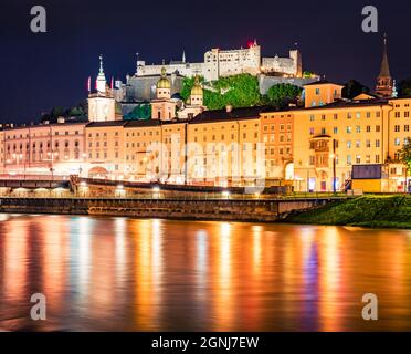 Die Altstadt von Salzburg spiegelt sich in den ruhigen Gewässern der Salzach wider. Unglaubliches nächtliches Stadtbild von Salzburg mit der Burg Hohensalzburg im Hintergrund. Au Stockfoto