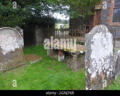 Auf dem Gelände der Monigaff (Minnigaff) Kirche oder Kirk, in der Nähe von Newton Stewart, Dumfries und Galloway. Die "neue" Kirche ist eine Kirche unter dem B-Denkmalschutz, die 1836 nach einem neugotischen Entwurf von William Burn erbaut wurde. Innerhalb des gleichen Geländes befinden sich die Ruinen der alten Kirche mit dazugehörigen Begräbnissen, die mit alten Grabsteinen markiert sind. Es wurde an der Stelle eines älteren motte- und bailey-Schlosses errichtet Stockfoto