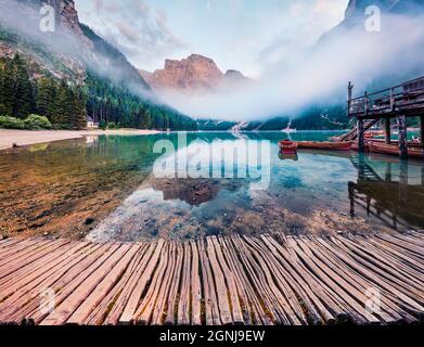 Nebliger Blick auf den Pragser Wildsee am Morgen mit altem Holzsteg. Malerische Sommerszene im Nationalpark Fanes-Sennes-Prags, Dolomiti Alpen Stockfoto