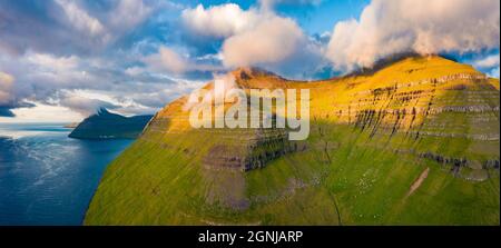 Panoramablick auf den Sommer von der fliegenden Drohne auf die Hügel des Dorfes Sydradalur, Insel Kalsoy. Niedrige Wolken Morgens Szene der Färöer Inseln, Dänemark, Europa. Beaut Stockfoto