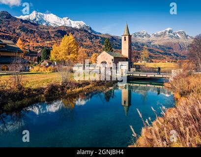 Orangefarbene Herbstszene der Kirche San Lurench in Sils im Engadin. Herrliche Aussicht auf die Schweizer Alpen am Morgen. Atemberaubende Landschaft des Sils-Sees, Schweiz Stockfoto