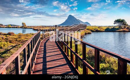 Wunderbarer Blick auf den Strand von Spiaggia di Porto Taverna im Sommer mit einer hölzernen Fußgängerbrücke. Erstaunliche Morgenszene der Insel Sardinien, Italien, Europa. Bild Stockfoto
