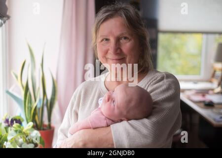 Ältere Großmutter, die ein Neugeborenes in den Armen hält Stockfoto