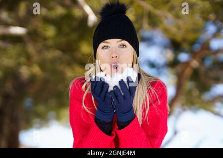 Junge Frau, die im Winter einen Schneeball bläst, in der Sierra Nevada, Granada, Spanien. Stockfoto