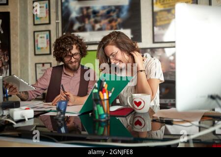 Junge, fröhliche Kollegen machen gemeinsam im Büro Schreibarbeit Stockfoto