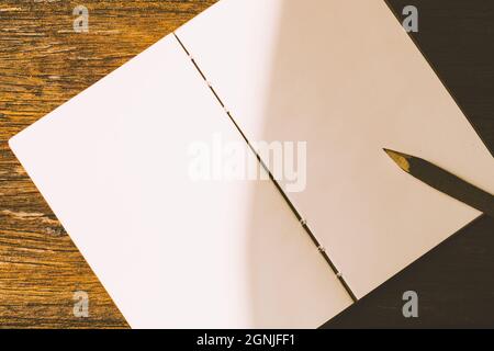 Ein Naturholzstift auf einem sauberen Stück weißem Papierbuch. Stockfoto