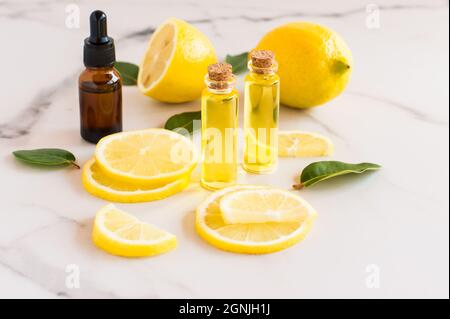 Zitrusöl, natürliche Zitrone, Vitamin C in Glasflaschen auf Marmorboden. Alternative Medizin Stockfoto