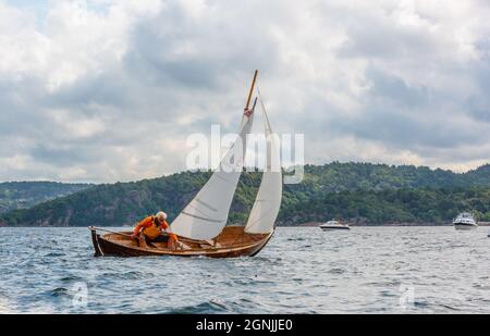 Lindesnes, Norwegen - August 08 2021: Mann steuert ein kleines Segelboot aus Holz Stockfoto