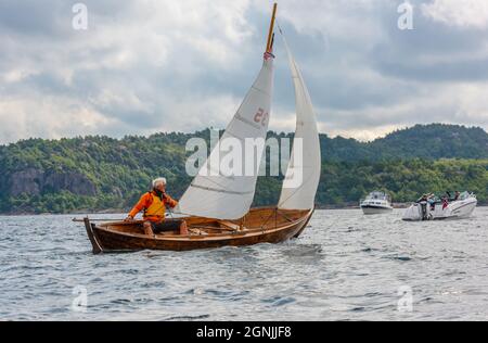 Lindesnes, Norwegen - August 08 2021: Mann steuert ein kleines Segelboot aus Holz Stockfoto