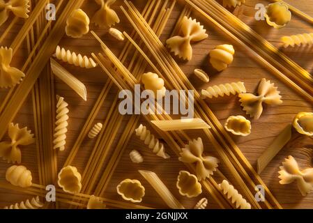 Verschiedene Arten von Pasta, auf Holztisch, mit Schatten und Highlights. Bild von oben Stockfoto