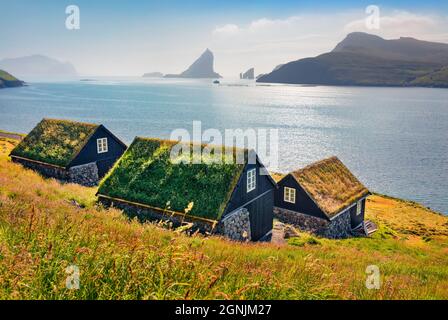 Atemberaubende Sommerszene von Bour Village mit typischen Turf-Top-Häusern und Tindholmur Klippen im Hintergrund. Faszinierende Morgenansicht der Insel Vagar, Stockfoto