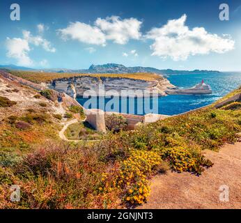 Wunderschöne morgendliche Szene von Ruinen der alten Bonifacio Festung mit dem Leuchtturm von Madonetta im Hintergrund. Herrliche Sommeransicht der Insel Korsika, Frankreich, Stockfoto