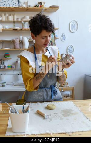 Kunst Hobby und Geschäft: Junge Frau tragen Schürze konzentriert auf Formglas in Keramik-Studio Stockfoto