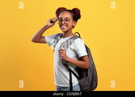 Happy afroamerikanische Schulmädchen mit Brille und Rucksack Stockfoto