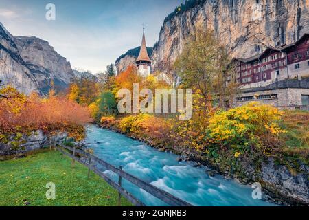 Farbenfrohe Herbstansicht des großen Wasserfalls im Lauterbrunnen Dorf mit azurblauem Fluss. Herrliche Outdoor-Szene in den Schweizer Alpen, Berner Oberland in der Luft Stockfoto