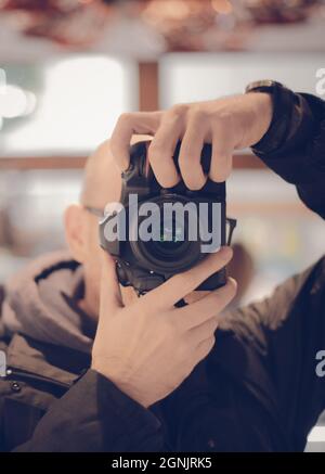 Nahaufnahme eines Menschen, der auf eine DSLR-Kamera mit hellem Hintergrund zeigt Stockfoto