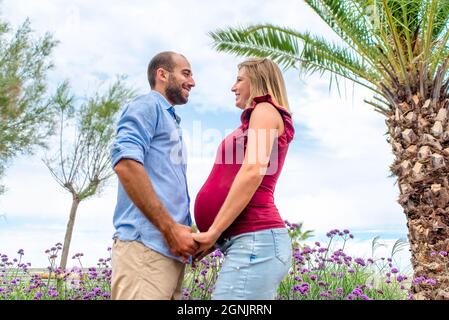 Glückliches Paar in der Liebe zu einer Schwangeren Frau und ihrem Freund halten die Hände Blick in die Augen im Freien. Qualität Familie Zeit hält die Hände Stockfoto