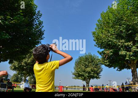 Srinagar, Kaschmir. September 2021. Ein Zuschauer beobachtet eine Flugshow der Kashmirn Air Force (IAF) mit einem Fernglas.die Show sah eine Ausstellung des Surya Kiran Aerobatics Teams der IAF, Paramotor und ein motorbetriebenes Drachenfliegen-Display, fliegen vorbei an MiG-21 Bison, Kunstflug mit Su-30 Flugzeugen. Es enthielt auch Akashganga Fallschirmspringen Display. Kredit: SOPA Images Limited/Alamy Live Nachrichten Stockfoto