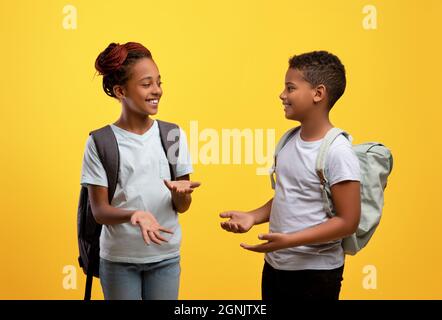 Glückliche afroamerikanische Schüler, die sich auf Gelb unterhalten Stockfoto
