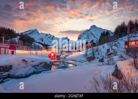 Verschneite Winterlandschaft der Stadt Nusfjord. Unglaublichesunset in Norwegen, Europa. Herrliche Abendansicht der Lofoten-Inseln mit roten Holzhäusern und sma Stockfoto