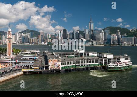 Eine Star Ferry kommt am Tsim Sha Tsui Pier in Kowloon an, mit Wan Chai und Causeway Bay, Hong Kong Island, sichtbar über den Victoria Hafen Stockfoto