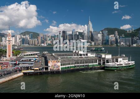 Eine Star Ferry verlässt den Tsim Sha Tsui Pier in Kowloon, mit Wan Chai und Causeway Bay, Hong Kong Island, sichtbar über den Victoria Hafen Stockfoto