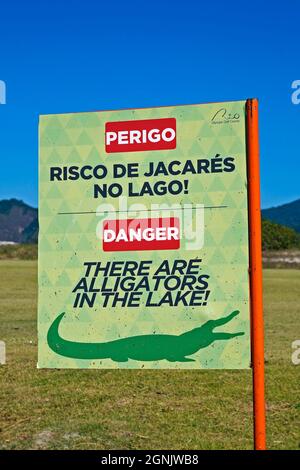 RIO DE JANEIRO, BRASILIEN - 16. DEZEMBER 2019: Schild warnt vor der Gefahr von Alligatoren im See. Rio Olympic Golf Course in Barra da Tijuca Stockfoto