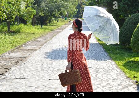 Vietnamesische Frau in traditionellen roten Polka dot Ao Dai, zu Fuß in den Komplex der Bai Dinh Pagode, Ninh Binh, Vietnam Stockfoto