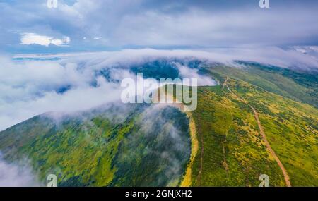 Düsterer Sommerblick von fliegender Drohne über den Wolken. Neblige Sommerszene der Svydovets-Bergkette. Malerischer Blick am Morgen auf die nebligen Karpaten Mo Stockfoto