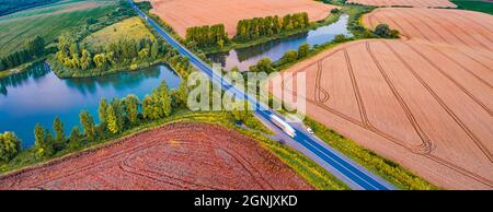 Landschaftsaufnahmen aus der Luft. Sommerpanorama von der fliegenden Drohne des Ternopil-Außenbezirkes mit zwei Seen und asphaltierter Straße. Atemberaubender Morgen-Scen Stockfoto