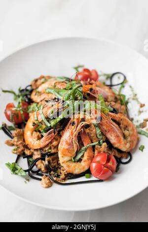 Spaghetti mit schwarzer Tintenfisch-Tinte, Garnelen und gemischtem Gemüse im Restaurant sizilien Stockfoto