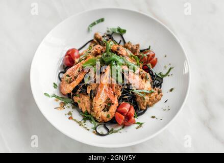 Spaghetti mit schwarzer Tintenfisch-Tinte, Garnelen und gemischtem Gemüse im Restaurant sizilien