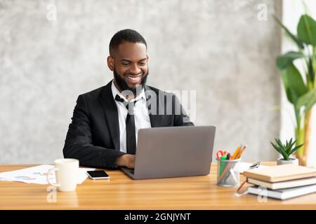 Afroamerikanischer Mann mit Laptop-Eingabe auf der Tastatur Stockfoto