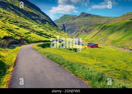 Wunderschöne Sommerlandschaft. Leere Asphaltstraße im Dorf Saksun. Fesselnde Morgenszene des Pollurin Canyon, Färöer Inseln, Dänemark, Europa. Travelin Stockfoto