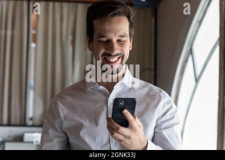 Glücklicher, selbstbewusster Millennial-Geschäftsmann, der im Online-Chat eine Textnachricht liest Stockfoto