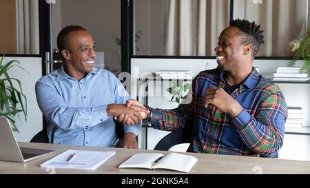 Glücklicher afroamerikanischer Kunde und Mitarbeiter, der das Treffen mit einem Handschlag abschreckt Stockfoto