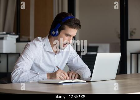 Fokussierter Student mit Kopfhörern, der im Internet studiert Stockfoto