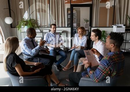 Mitarbeiter des multiethnischen Geschäftsteams sitzen im Kreis im Büro Stockfoto