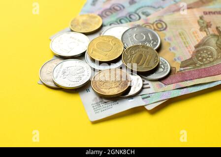 Russische Rubel auf gelbem Hintergrund. Banknoten und verschiedene Münzen. Stockfoto