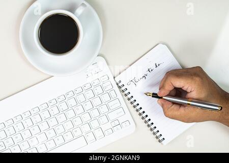 Konzept „Arbeiten von zu Hause aus“. Handschriftlich in einem Notizbuch, einer Tastatur und einer Tasse Kaffee. Selektive Fokuspunkte Stockfoto